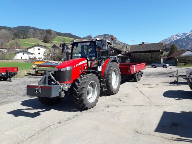 Tiefbau-Traktor mit Transportanhänger im Einsatz vor Alpenkulisse