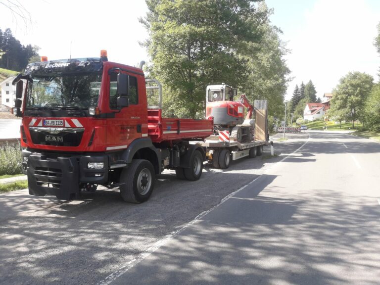 Transportfahrzeug der Becherer Tiefbau GmbH mit Tieflader und Minibagger auf Landstraße im Allgäu